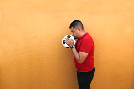 Latino adult man plays with a soccer ball very excited that he is going to see the World Cup and wants to see his team winの写真素材