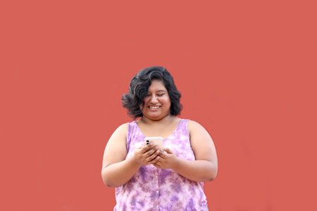 Young 20 year old Latina brunette woman uses her cell phone to send messages, make calls, buy, pay, study and make appointmentsの写真素材