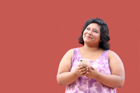 Young 20 year old Latina brunette woman uses her cell phone to send messages, make calls, buy, pay, study and make appointmentsの写真素材