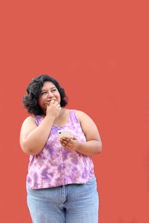 Young 20 year old Latina brunette woman uses her cell phone to send messages, make calls, buy, pay, study and make appointmentsの写真素材