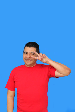 Dark-skinned Latino adult man makes the victory sign with his fingers happy and excited