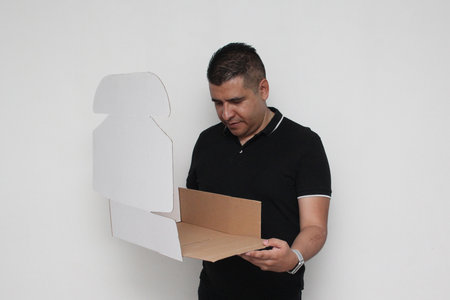 Latino adult man assembles a cardboard box following the instructions to achieve it