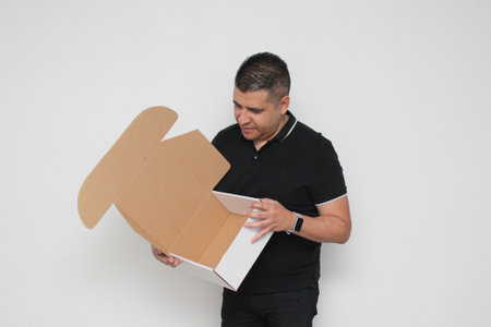 Latino adult man assembles a cardboard box following the instructions to achieve it