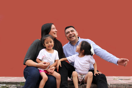 Family of dad, mom and two dark-skinned Latino daughters enjoy quality time together laugh and have...