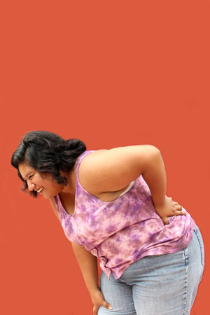 Young brunette Latin woman of 20 years old suffers from back, spine and neck pain due to tension and...