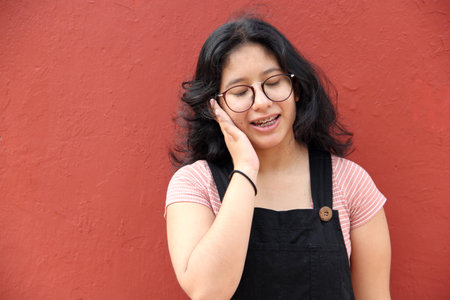 Young 17-year-old Latin woman suffers from ear pain due to acute or chronic infection due to the use...