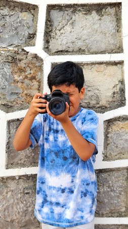 10-year-old dark-skinned Latino boy learns to use a professional camera, dreams and imagines working...