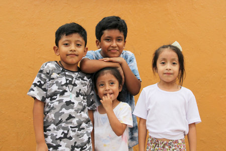 Two happy and excited dark-skinned Latino boys and 2 girls celebrate Children's Day by playing and...