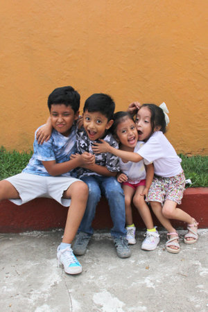 Two happy and excited dark-skinned Latino boys and 2 girls celebrate Children's Day by playing and laughingの写真素材