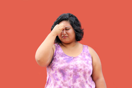 Young 20 year old Latin brunette woman suffers from nasal congestion and pain when she blocks her nose which causes difficulty breathing through the nostrils due to sinusitisの写真素材