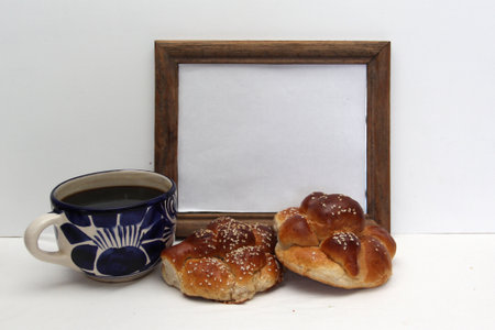 Hot coffee in an artisan cup with fluffy and delicious bread of the dead with sesame in offering of the Day of the Dead with decoration of cempasuchil and colored cut-out paperの写真素材