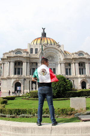Mexico City, Mexico - Sep 6 2023: Man holds the Mexican flag in front of the Palacio de Bellas Artes to celebrate the national holidays of independence and revolutionのeditorial素材