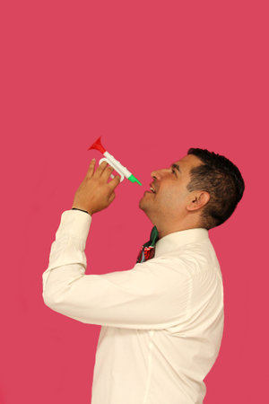 Dark-skinned Latino adult man plays a toy tricolor trumpet with a bow with the colors of the Mexican...