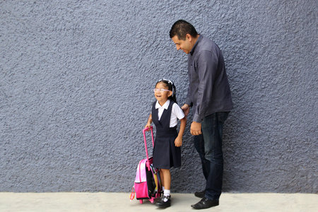 Divorced single dad walks to school with his 4 year old brunette daughter carrying her backpack for back to schoolの写真素材