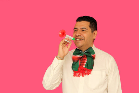 Mexican adult man with tricolor bow and toy trumpet celebrates the national holidays of Mexican...