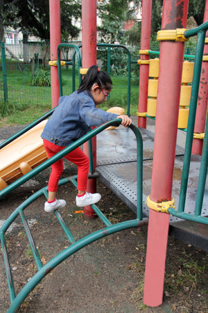 4 year old Latina brunette girl with glasses plays in park games enjoys weekend on vacation