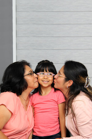 Three Generations of women Grandmother, mom and brunette Latina daughter with glasses show their...