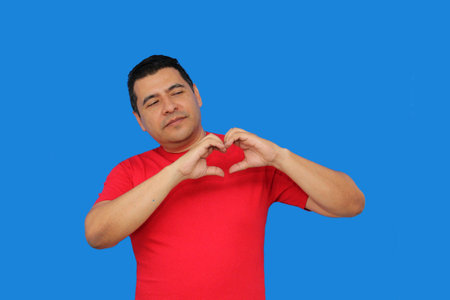 Dark-skinned Latino adult man makes a heart sign with his fingers as a sign of love and affection