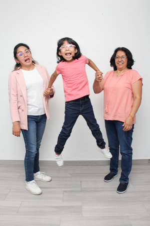 5-year-old Latin girl has the support of her dark-skinned mother and grandmother with glasses for care and educationの写真素材
