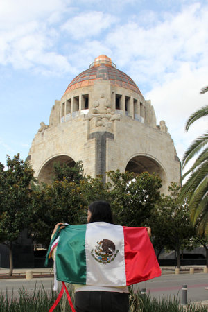 Latina adult woman shows the flag of Mexico with pride to celebrate the national holidays of Mexican Independence Day and Cinco de Mayoの写真素材