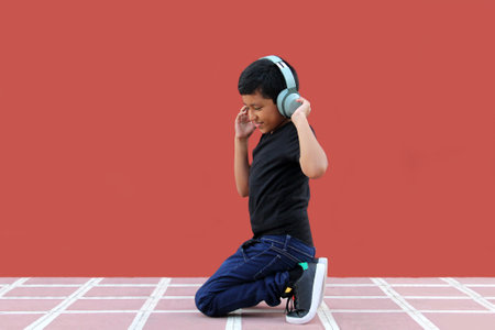 9-year-old dark-skinned Latino boy uses noise-isolating headphones for autism, calm in solitudeの写真素材