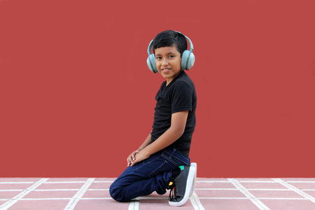 9-year-old dark-skinned Latino boy uses noise-isolating headphones for autism, calm in solitude,...
