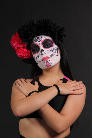 Young Mexican woman made up as Catrina or skull with flower crown to celebrate the Day of the Dead...