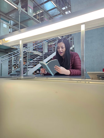 Single 40 year old Latina woman reads books in the library for study and hobby to acquire knowledge...