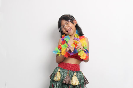 5 year old Latina brunette girl with glasses and Hawaiian skirt enjoys dancing and does Hawaii dance steps very happy and excitedの写真素材