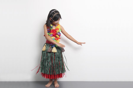 5 year old Latina brunette girl with glasses and Hawaiian skirt enjoys dancing and does Hawaii dance steps very happy and excitedの写真素材