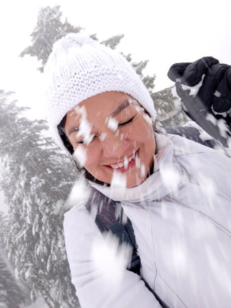 Latin adult woman plays throwing snowballs in the snow due to a cold wave, low temperatures and freezingの写真素材