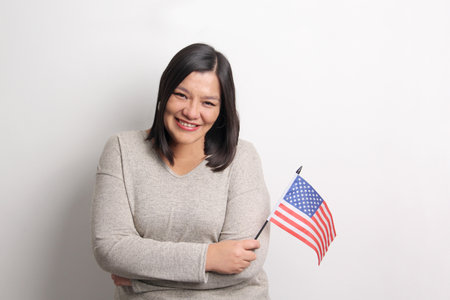 40-year-old Latina woman shows the United States flag proud and happy to obtain nationality to...