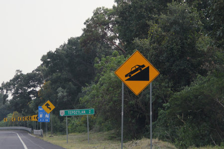 Dangerous slope sign is a traffic sign that warns drivers that the road has a steep slope in mountainous areas or with uneven terrainの写真素材
