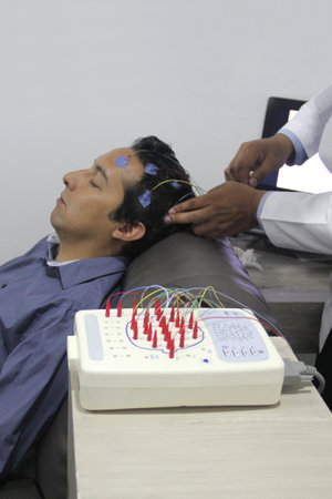 Electroencephalogram EEG in adult Latino man with wires in his head, medical study that records the...