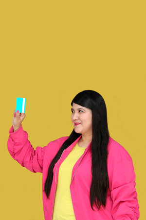 Latin adult woman with long hair shows her credit card that she uses to make purchases and payments