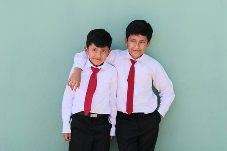 8 and 10 year old Latino children dressed in school uniforms are happy and excited about going back to schoolの写真素材