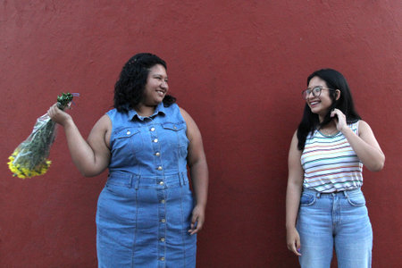 Young Latina sisters and friends, brunettes, give each other yellow flowers to show their love and the arrival of springの写真素材