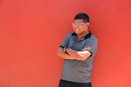 A 30-year-old dark-skinned Latino man with glasses appears happy and successful as an...
