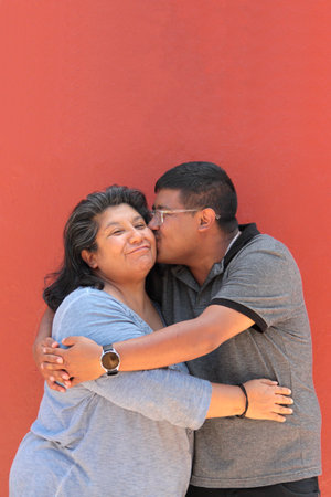 A 50-year-old single mother and her 30-year-old dark-skinned Latino son show their love and celebrate Mother's Day togetherの写真素材