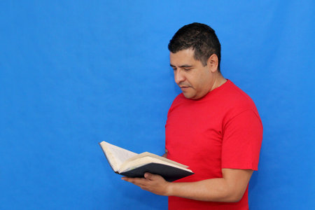 40-year-old dark-skinned Latino man reads and books and enjoys reading to learn, study, and gain knowledge for personal and professional growthの写真素材