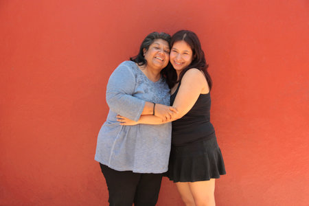 Single mother and her 18-year-old Latina daughter show their love with kisses and hugs and celebrate Mother's Dayの写真素材