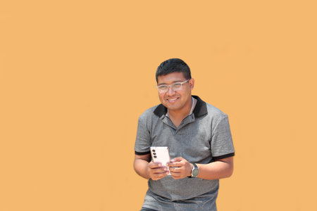 30-year-old dark-skinned Latino man with glasses uses his cell phone to work remotely, make calls,...
