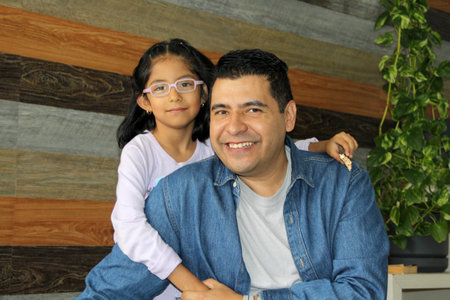 Divorced single dad plays with his 5-year-old Latina daughter, a brunette with glasses, showing their love and celebrating Father's Dayの写真素材