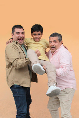 Three generations of a dark-skinned Latino grandfather, father, and son show their love and spend time togetherの写真素材