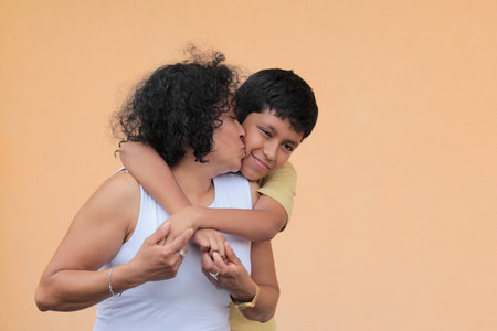 A single mother and her 9-year-old Latino son show their love with hugs and kisses to celebrate Mother's Dayの写真素材