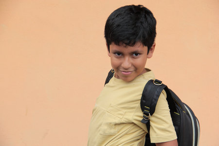 10-year-old Latino boy, excited and happy, uses his backpack with books to study and learn back to schoolの写真素材
