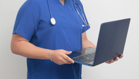 A dark-skinned Latino male specialist doctor uses a laptop to work on video call consultations, search for information, and studyの写真素材