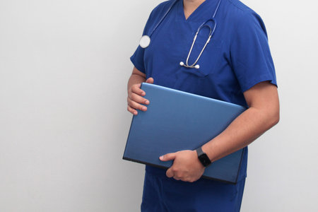 A dark-skinned Latino male specialist doctor uses a laptop to work on video call consultations, search for information, and studyの写真素材