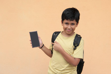 A 10-year-old boy uses his cell phone to play video games, make video calls, send messages, and take selfiesの写真素材