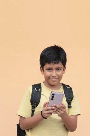 A 10-year-old Latino boy uses his cell phone to play video games, make video calls, send messages, and take selfiesの写真素材